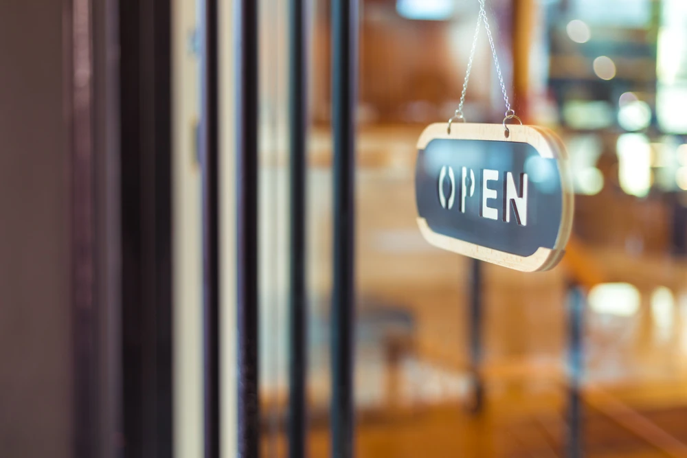 Intérieur de commerce avec panneau "OPEN" suspendu à une chaîne devant une vitrine