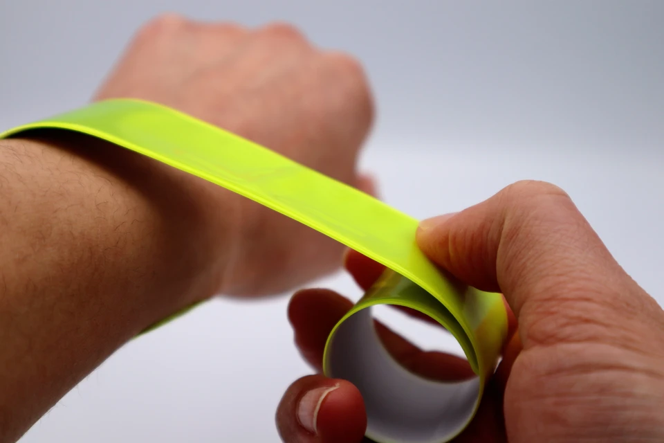 Mains manipulant un adhésif repositionnable jaune fluorescent sur fond blanc neutre